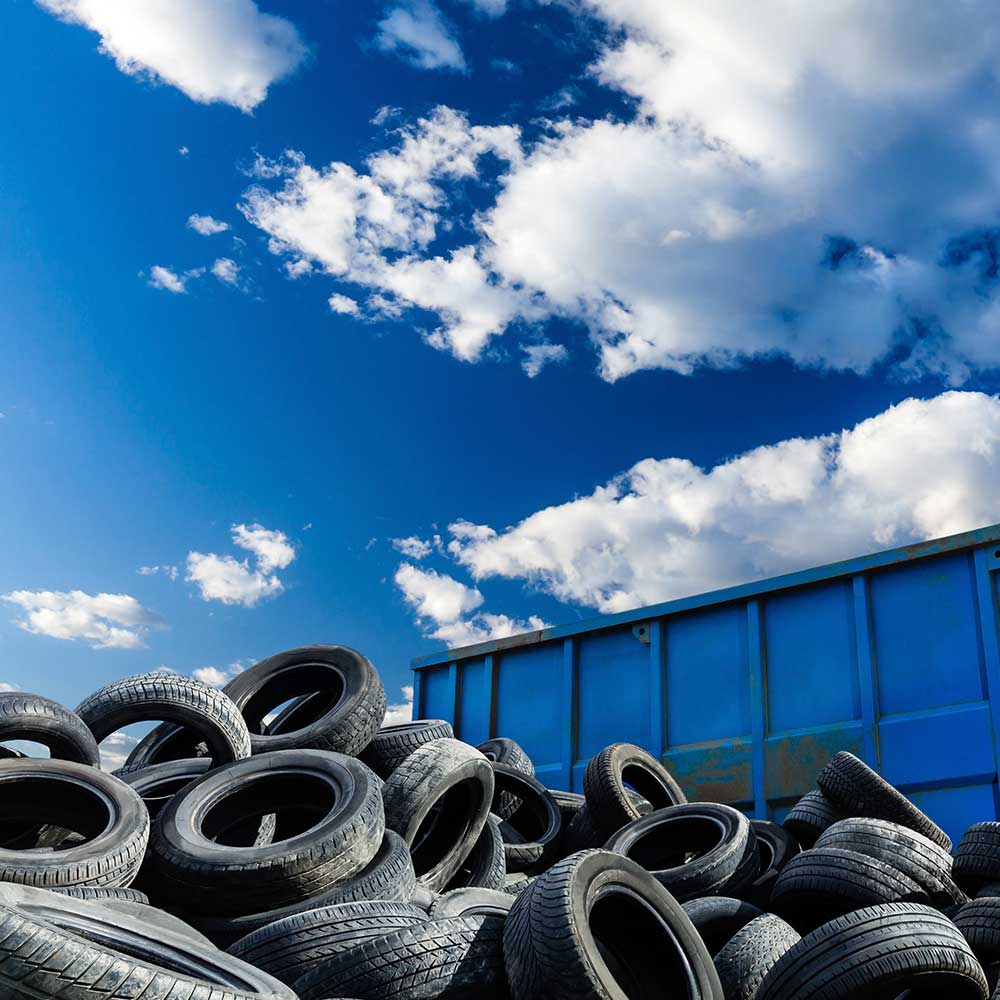 A stack of tires with blue sky and clouds above